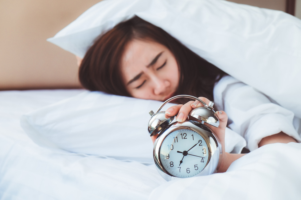 Young Woman Sleeping with Alarm Clock in the Bedroom